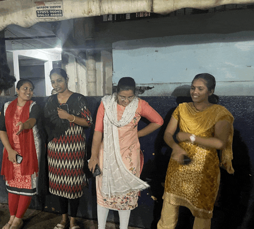 a group of women are standing in front of a building with a sign that says ' shree ram '