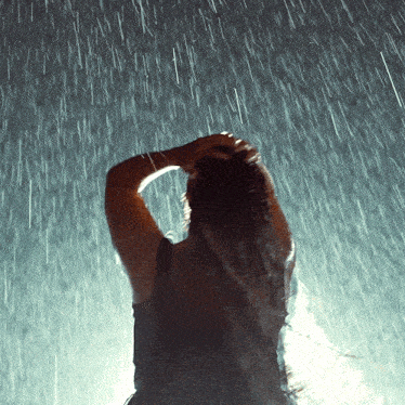 a woman standing in the rain with her hands on her head