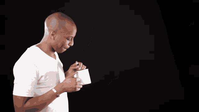 a man in a white shirt is holding a cup and a spoon