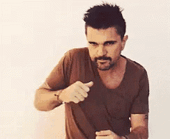 a man with a beard is pointing his finger at the camera .