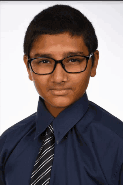 a young man wearing glasses and a blue shirt and tie