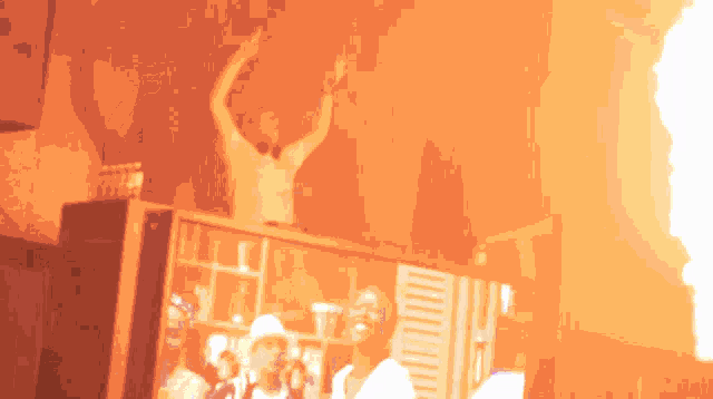 a man with his arms in the air stands in front of a tv screen