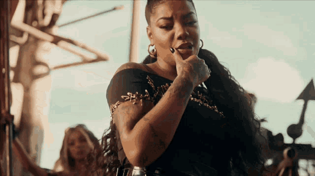 a woman with long hair and a tattoo on her arm is singing into a microphone