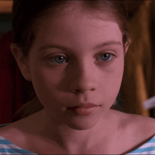 a close up of a girl 's face with blue eyes and a striped shirt