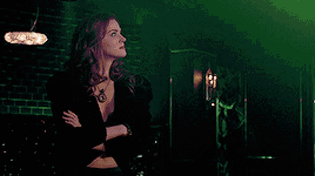a woman is standing with her arms crossed in a green room