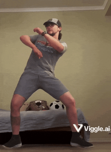 a man in a gray shirt and shorts is dancing with a viggle.ai logo in the corner