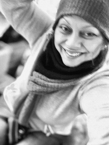 a woman wearing a beanie and scarf smiles for the camera