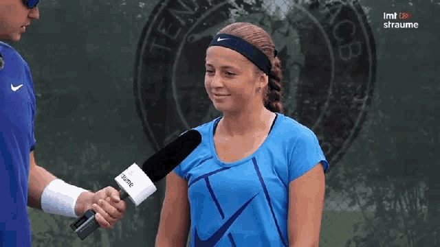 a woman in a blue shirt is being interviewed by a man