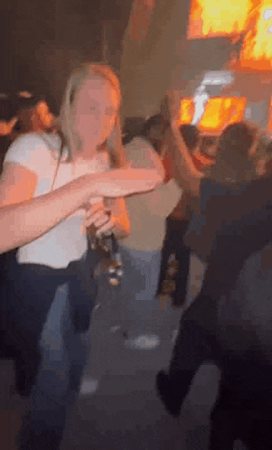 a woman is standing in a crowd of people at a party holding a glass of beer .
