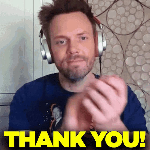 a man wearing headphones is clapping his hands in front of a thank you sign