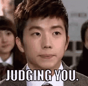 a man in a suit and tie is making a funny face with the words judging you .