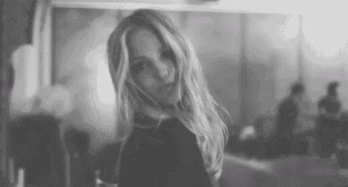 a black and white photo of a woman with long blonde hair looking at the camera .