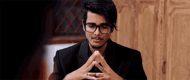 a man with glasses and a ring on his finger looks down