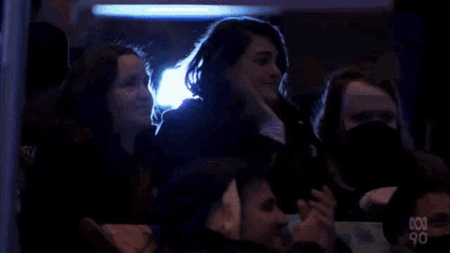 a group of people wearing masks are sitting in a stadium watching a concert .