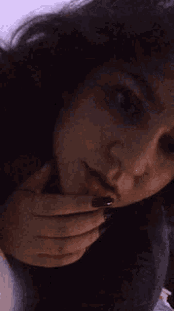a close up of a woman 's face with her hands on her face .
