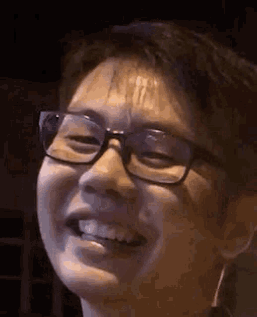 a close up of a man wearing glasses smiling at the camera .
