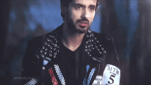 a man with a beard wears a black leather jacket with mtm written on it
