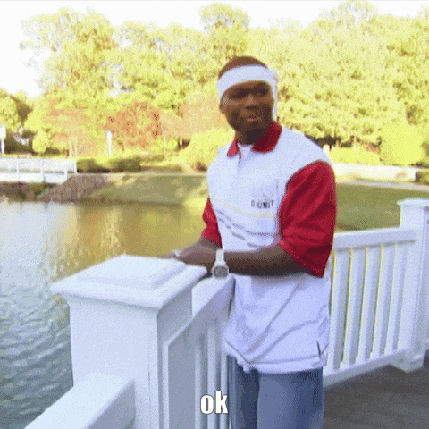 a man wearing a shirt that says 50 cent stands on a railing overlooking a lake