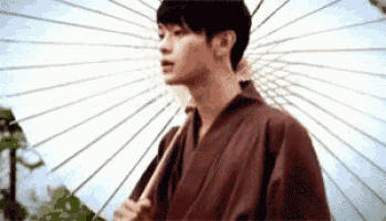 a man in a brown kimono is holding an umbrella