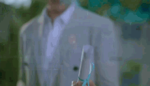 a man in a suit and white shirt is standing in front of a green background .