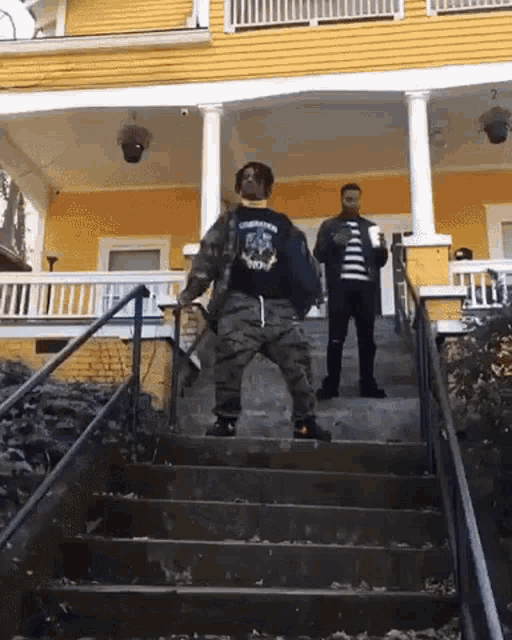 two men are standing on the steps of a house .
