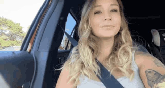 a woman with a tattoo on her arm is sitting in a car