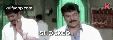 two men are standing next to each other in a room and one of them is shocked while the other is laughing .