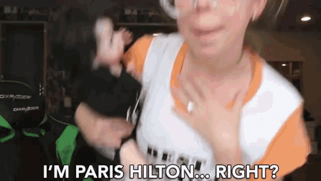 a woman says i 'm paris hilton right in front of a green dxracer chair