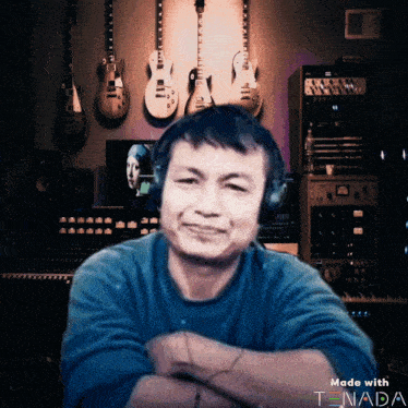 a man wearing headphones in front of a wall of guitars with the words made with tnada below him