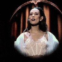 a woman in a white corset is singing on stage