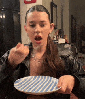 a woman is eating from a blue and white plate