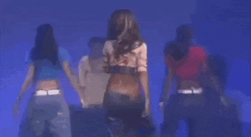 a group of women are dancing together on a stage in a dark room .