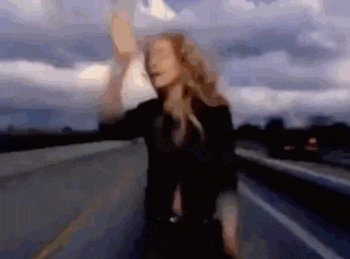 a blurry picture of a woman standing on the side of a highway
