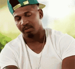 a man wearing a white t-shirt and a green hat is looking down .