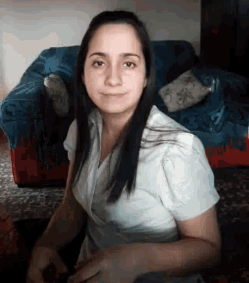 a woman in a white shirt is sitting in front of a red and blue couch
