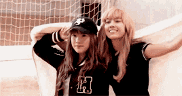 two girls are posing for a picture with one wearing a hat with the letter p on it