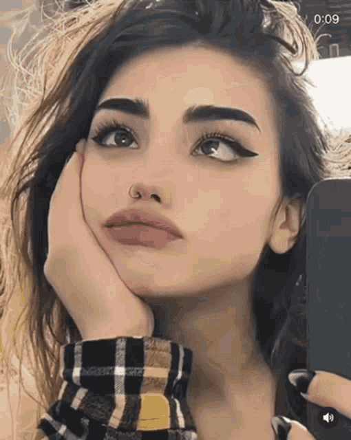 a woman with a nose ring is taking a selfie with her phone