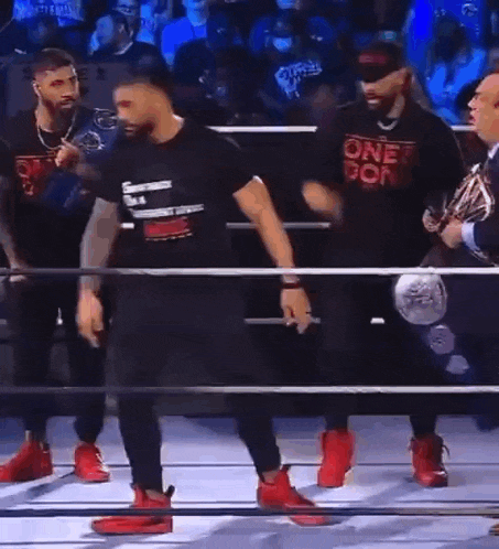 two men are dancing in a wrestling ring with a crowd watching .