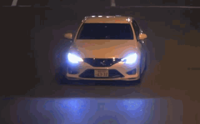 a white car with a license plate that says 41-17 is driving down the road at night