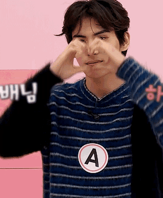 a man wearing a striped shirt with the letter a on it covering his nose