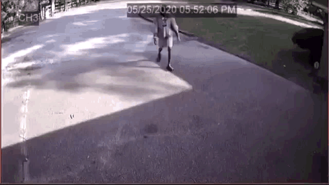 a person is walking down a sidewalk in front of a house in a video .