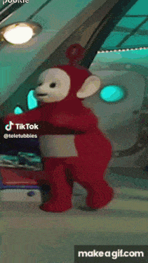 a red teletubbies teddy bear is standing in front of a window with a make a gif.com button below it