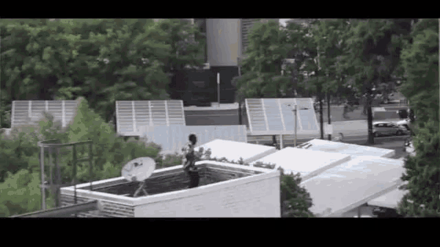a man is standing on a roof with a satellite dish in the background