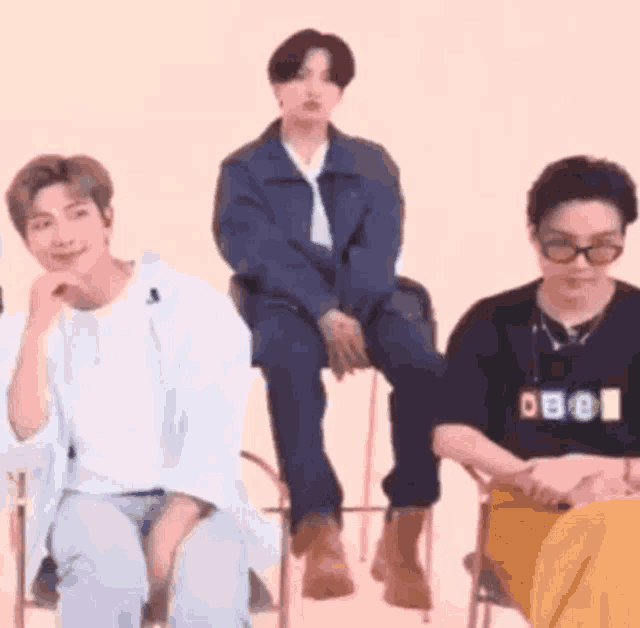 a group of young men are sitting on chairs and talking to each other .
