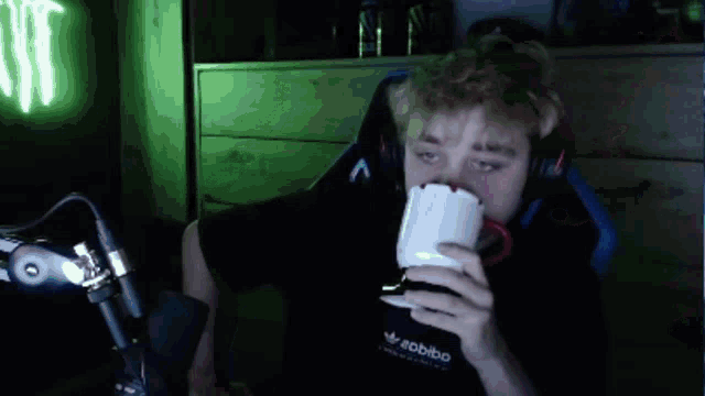 a man is sitting in a chair drinking from a white mug .