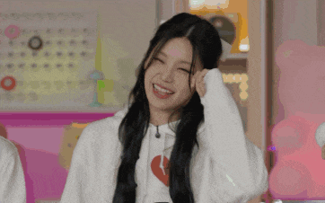 a woman wearing a white sweatshirt with a heart on it is smiling