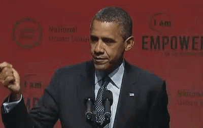 a man in a suit and tie is giving a speech in front of two microphones .