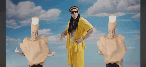 a man in a yellow shirt is surrounded by two men dressed in finger costumes