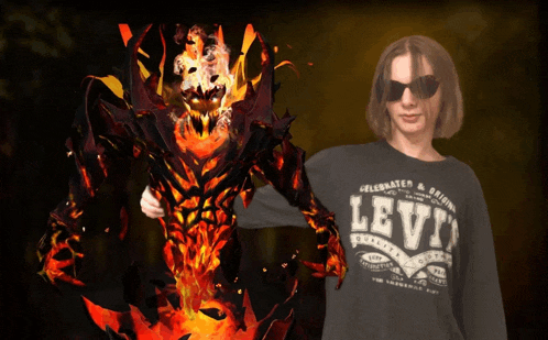 a person wearing a black levi 's shirt stands next to a fire monster