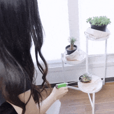 a woman is holding a green lighter in front of a plant stand